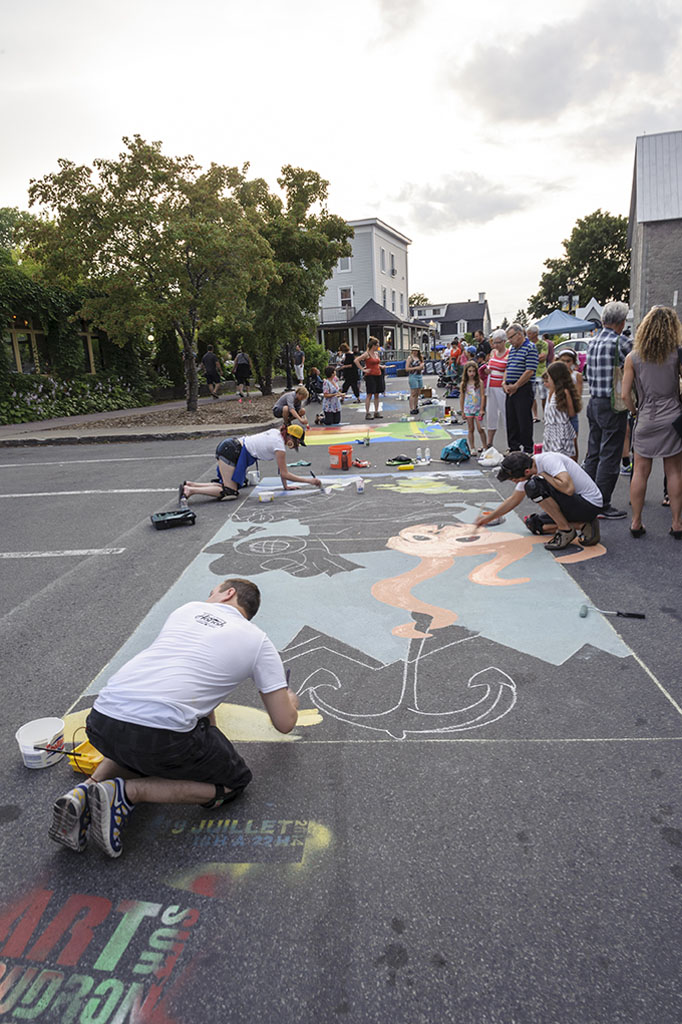 Un artiste peint en direct dans les rues du Vieux-Beloeil à l'occasion de l'événement L'art sur Goudron.