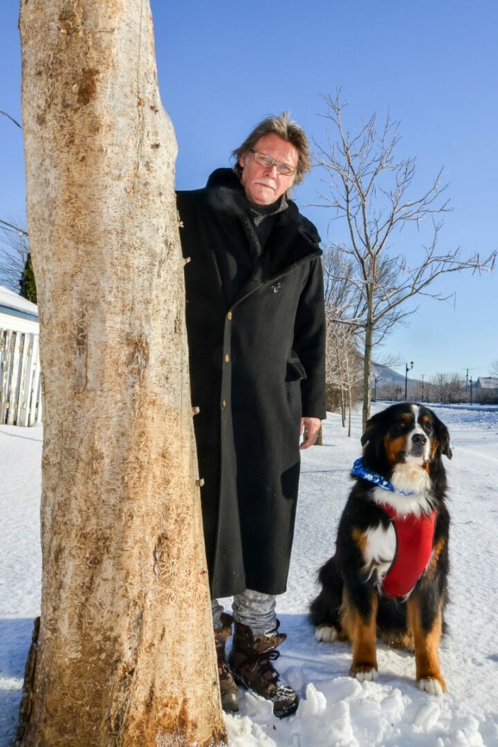 Daniel-Vincent Bernard, en compagnie de son chien Amos, à côté d'un des arbres qu'il sculptera très prochainement au bord de la rue Saint-Jean-Baptiste à Belœil.
Photo: François Larivière