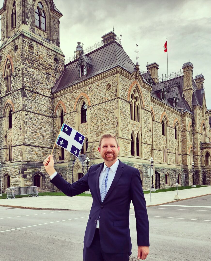 Xavier Barsalou-Duval devant le parlement avec son drapeau du Québec. Photo gracieuseté.