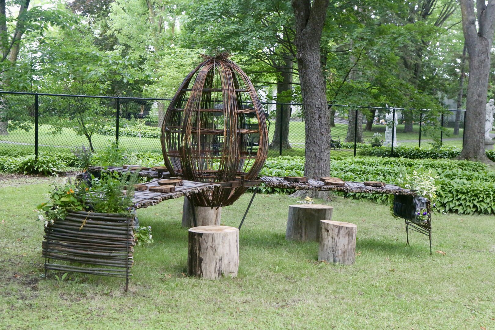 Dans le jardin du monastère, l’artiste hilairemontais André Boisvert a créé « Vivre à table », une œuvre inspirée du land art invitant le public à revivre le rituel de se retrouver à table pour un repas. Photo Robert Gosselin | L’Œil Régional ©